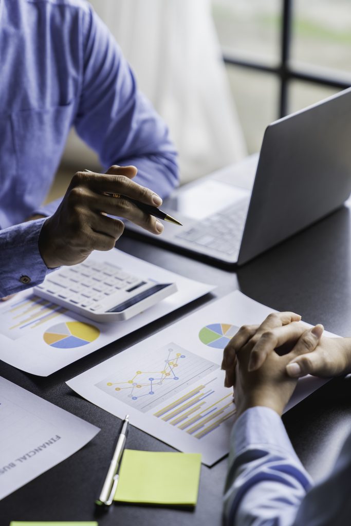 Paperwork and hands on a board room table at a business presentation or seminar. analysis report Che